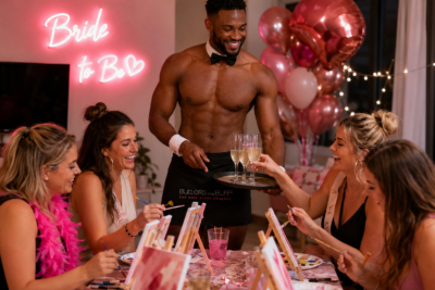 Male butler serves drinks to women celebrating a hen party at a decorated table.