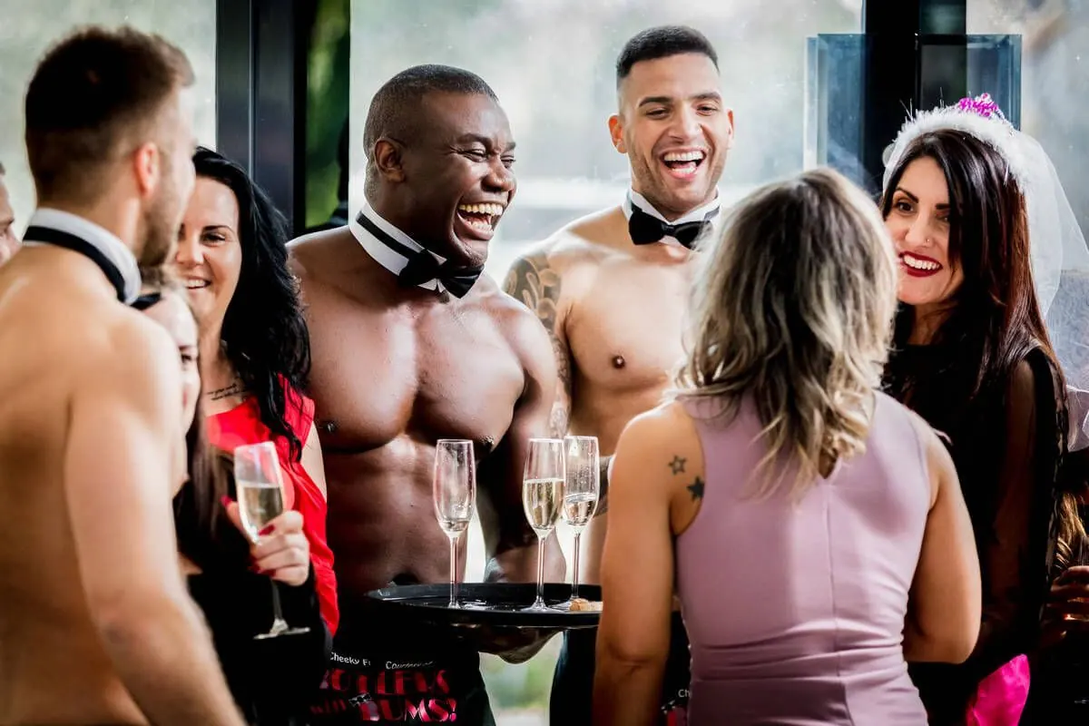 Butlers in the Buff serving champagne to laughing hen party guests and the bride-to-be