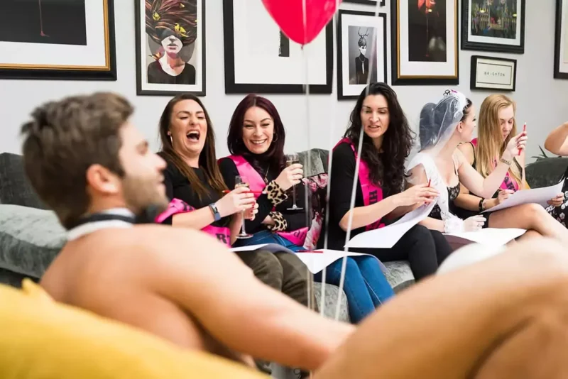 Hen party guests laughing as they sketch a Butler in the Buff during a life drawing class